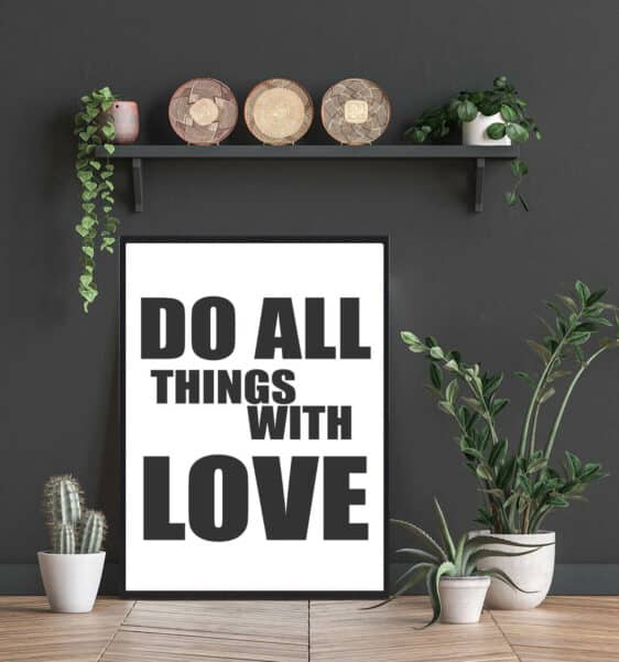 Framed 'Do All Things With Love' art print. Black text on white background, styled with plants and woven baskets for modern home decor.