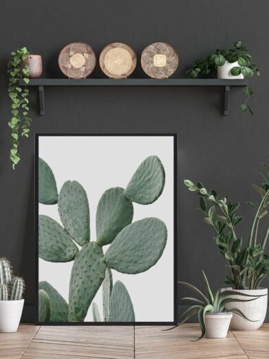 Cactus in Desert Naturplakat: Close-up of a green prickly pear cactus print in a black frame, displayed in a stylish interior setting.