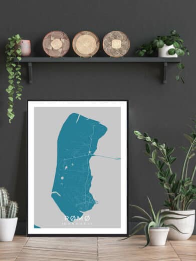 Rømø plakat: A teal map of Rømø, Denmark, on a gray background, framed in black. Displayed with plants and decorative baskets.