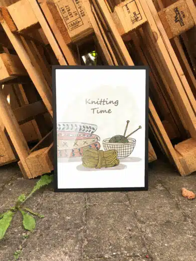 Strikkeplakat med citatet "Knitting Time" samt garnnøgler, en kurv og strikkepinde