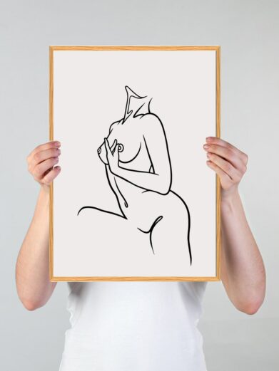 Line art plakat: Minimalist black line drawing of a nude female figure on a white background, framed in light wood, held by hands.