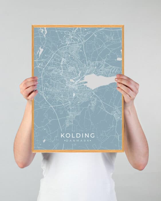 Grøn Kolding plakat med detaljeret bykort i lyseblå og hvid, holdt af hænder. Rammen er i træfarve. Moderne design.