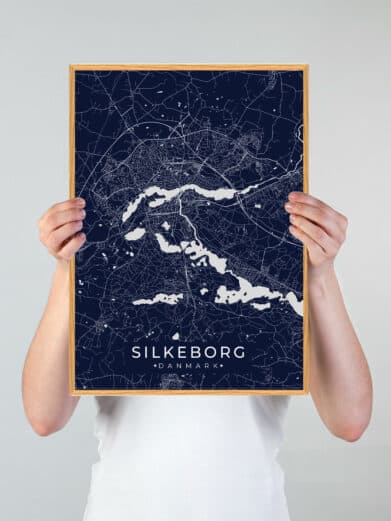 Mørkeblå Silkeborg plakat med hvide kortdetaljer og træramme. Viser byens gader og søer. Perfekt grøn by dekoration!