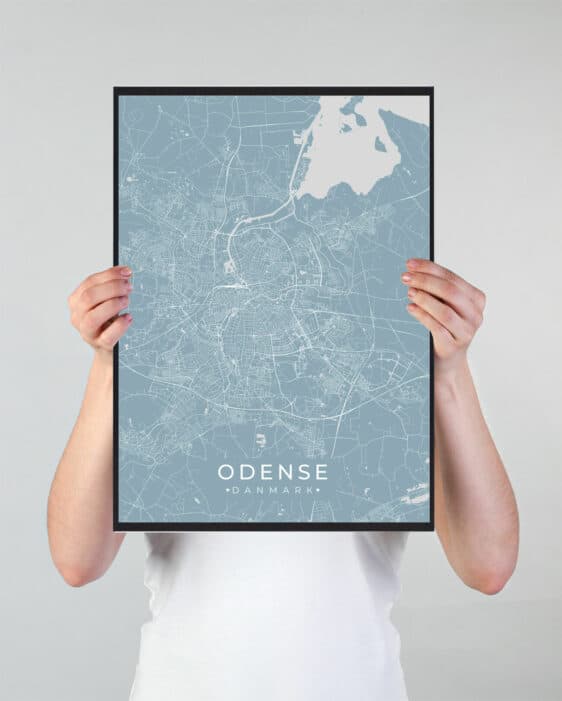 Odense poster: A person holds a framed map of Odense, Denmark. The map is light blue with white roads and a black frame.